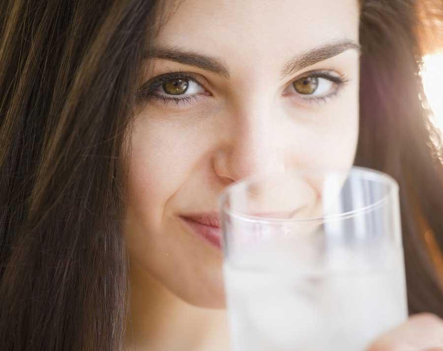 Woman raising a glass of sparkling clean water