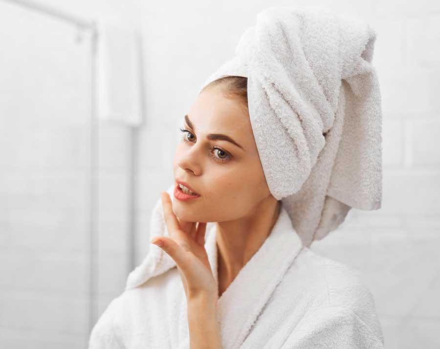 Woman after shower in bright white robe and towel